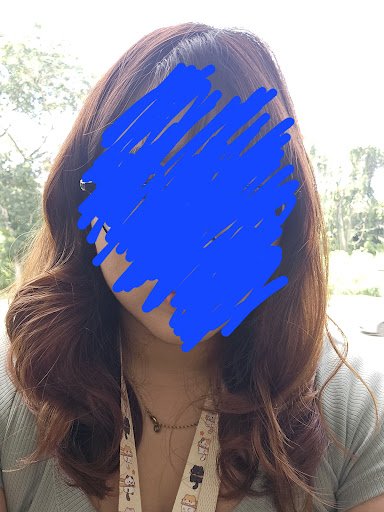 A person is standing outdoors wearing a lanyard and casual clothing.