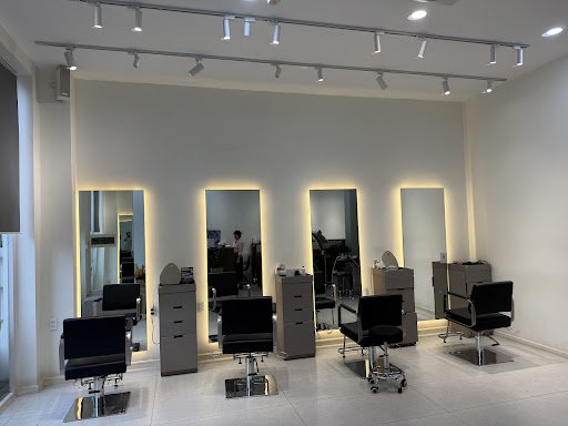 The image shows a modern hair salon interior featuring multiple styling stations equipped with mirrors and professional lighting.
