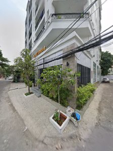 Exterior view of a multi-story building in Thao Dien, Saigon. The building features balconies, a ground-floor commercial space with a small garden are