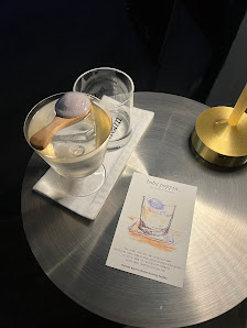 A close-up view of a table in an indoor setting featuring two glasses and a small bowl with what appears to be ice cream, accompanied by a card that l