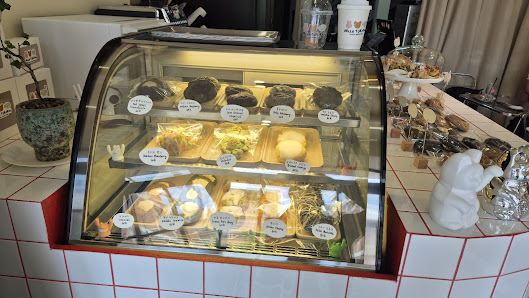 The image shows a display case in an interior setting of what appears to be a café or bakery. The glass-fronted, curved-top display case is filled wit