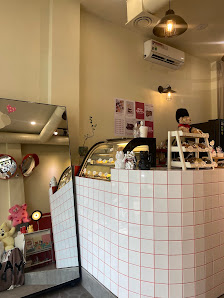 The image shows an interior view of a cafe or bakery shop in Thao Dien, Saigon. The decor features white tiled walls and various display cases showcas