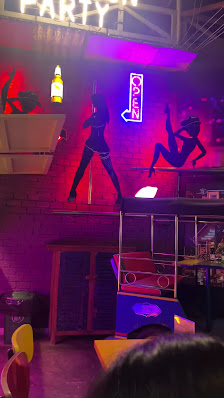 The image depicts an interior view of a venue in Thao Dien, Saigon with vibrant neon lights and modern decor elements such as brick walls and colorful