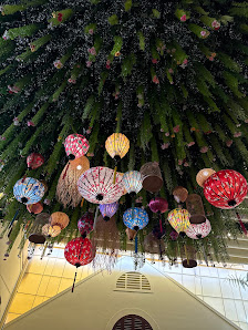 The image depicts an interior space of a venue in Thao Dien, Saigon, featuring a large, lush green installation (possibly a tree or decorative structu