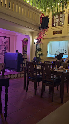 The image depicts the interior of a venue in Thao Dien, Saigon. It features wooden dining tables and chairs arranged for guests, a stage area with a p