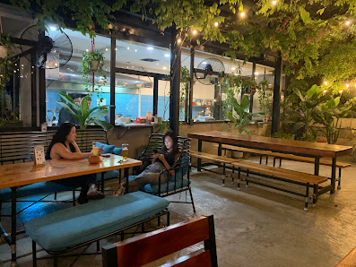 The image shows an indoor seating area of a cafe or restaurant in Thao Dien, Saigon. There are wooden tables and benches with green cushions, and the