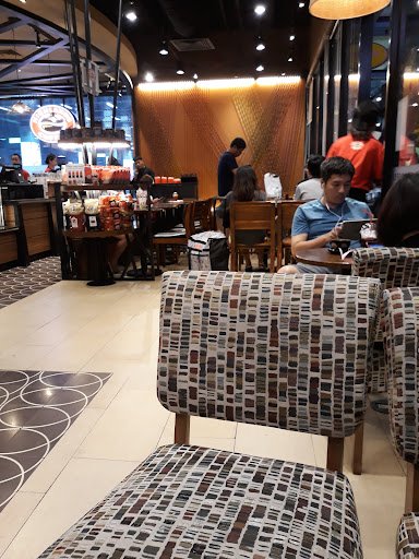The image shows an interior view of a modern café or restaurant in Thao Dien, Saigon. The seating area features patterned chairs and tables with vario