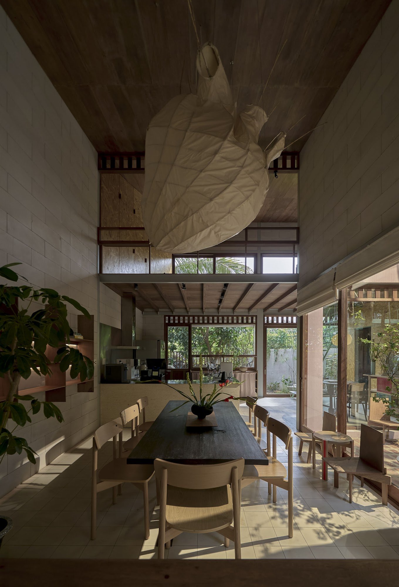 This image depicts an interior space that appears modern and minimalist in design. The room features a high ceiling with exposed wooden beams, large w