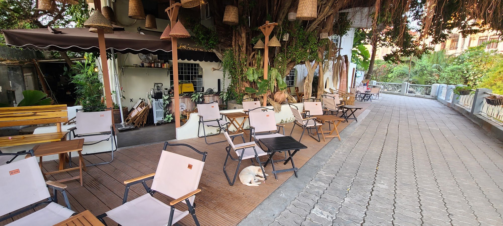 The image depicts an outdoor seating area of a restaurant or café in Thao Dien, Saigon. The setting is casual with various types of chairs and tables 