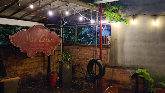 An outdoor venue in Thao Dien, Saigon featuring a rustic setting with brick and concrete walls, string lights hanging from a metal structure, a wooden