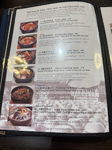 A menu displayed on a table at Thao Dien in Saigon showing various Korean dishes with accompanying images and descriptions.