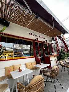 The image shows an exterior view of a restaurant named 'Vinós Táras' with outdoor seating arrangements including tables and chairs, as well as potted 