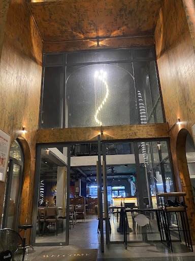 The image shows an interior view of a modern café or restaurant located in Thao Dien, Saigon. The entrance features large glass doors with metal frame