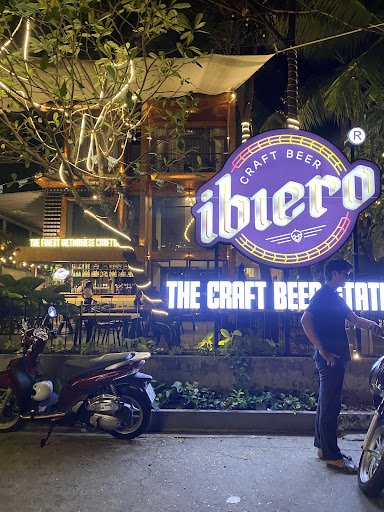 The image depicts the exterior of a craft beer venue at night in Thao Dien, Saigon. A prominent neon sign displays 'ibero craft beer' with 'THE CRAFT 