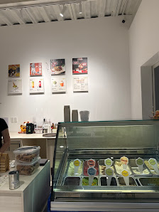 The image shows an interior view of a modern ice cream shop or dessert parlor with various flavors displayed in a refrigerated case, and several menu 