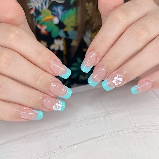 A close-up of a person's manicured nails featuring pastel blue and pink colors with white floral accents on the tips.