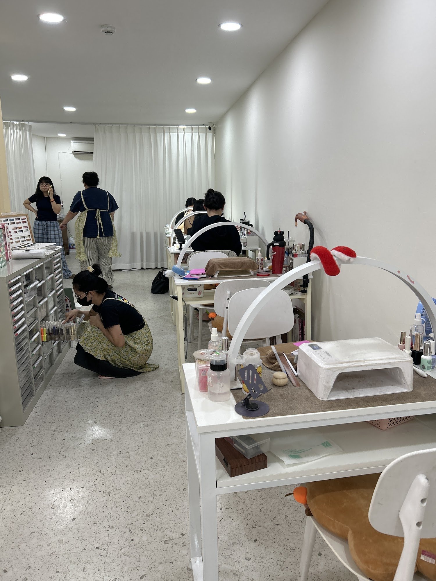 A well-lit interior of a beauty salon or makeup studio in Thao Dien, Saigon. The room features white walls, recessed ceiling lights, and multiple whit