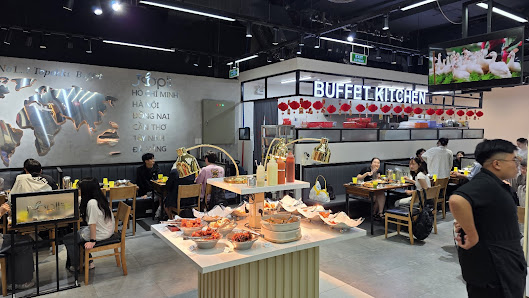 The image shows an interior view of a modern buffet-style restaurant named 'BUFFET KITCHEN'. The decor includes large murals on the walls, red lantern