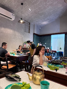The image shows an indoor dining area where several people are seated at a table enjoying their meal.