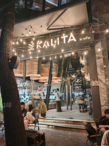 The image depicts the exterior of KALITA kafe, a café located in Thao Dien, Saigon. The storefront features large glass windows showcasing the interio
