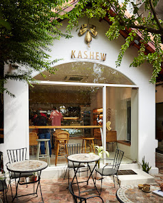 The image depicts the exterior of KASHEW, a venue in Thao Dien, Saigon. It features a white facade with a glass front entrance, displaying the name "K