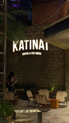 The image shows an exterior view of a coffee and tea house named 'KATINAi' at night time with outdoor seating arrangements visible in front.