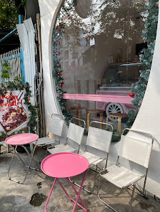 The image shows an outdoor seating area of a cafe or food truck in Thao Dien, Saigon. There are two pink round tables with white chairs around them on