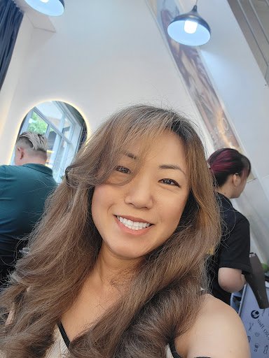 A woman is taking a selfie inside what appears to be an interior space of Thao Dien in Saigon. The background shows other patrons and the decor includ