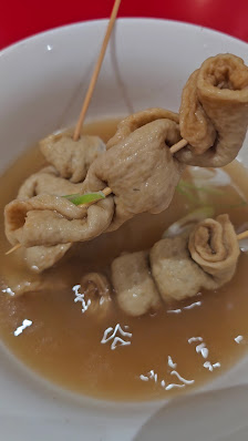A close-up of a dish featuring what appears to be meatballs or dumplings in a broth with some green garnish visible on top.