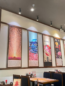 The image depicts the interior of a restaurant or café in Thao Dien, Saigon. It features a wall with four framed artworks depicting Japanese-inspired 