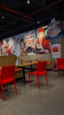 The image depicts the interior of a casual dining venue in Thao Dien, Saigon. It features bright red chairs and tables arranged on a polished concrete
