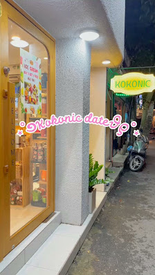 The image depicts the exterior of a shop in Thao Dien, Saigon. On the left, there's a storefront with a glass window showcasing various items (possibl