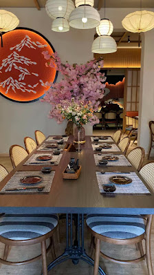 The image shows a well-lit dining area featuring wooden furniture and decor that suggests an Asian-inspired theme.