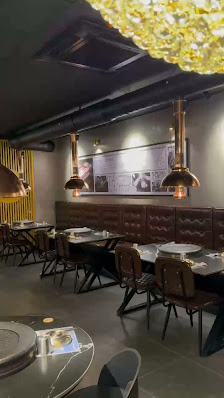 The image shows an interior view of a modern restaurant or dining establishment in Thao Dien, Saigon. The space features dark wooden tables and chairs