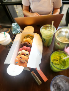 A person is seated at a table in what appears to be an indoor cafe or restaurant setting with various food items and drinks on the table.