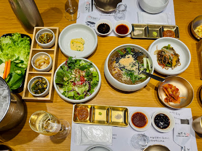 A table set for a meal featuring various Korean dishes including kimchi, salad, and banchan (side dishes). The setting appears to be in Thao Dien, Sai