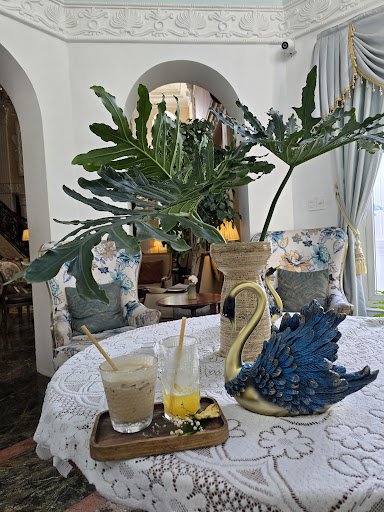 The image depicts an elegant interior setting featuring a round table adorned with various items such as drinks and decorative pieces including a blue
