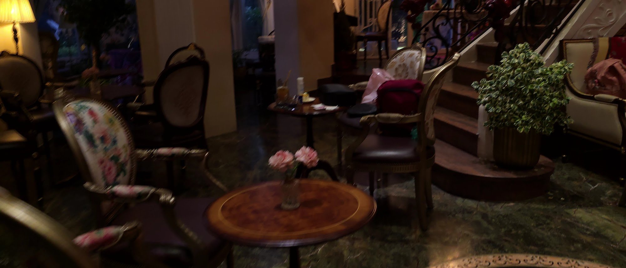 The image depicts a dimly lit interior space, likely a lounge or reception area in a venue in Thao Dien, Saigon. It features vintage-style furniture i