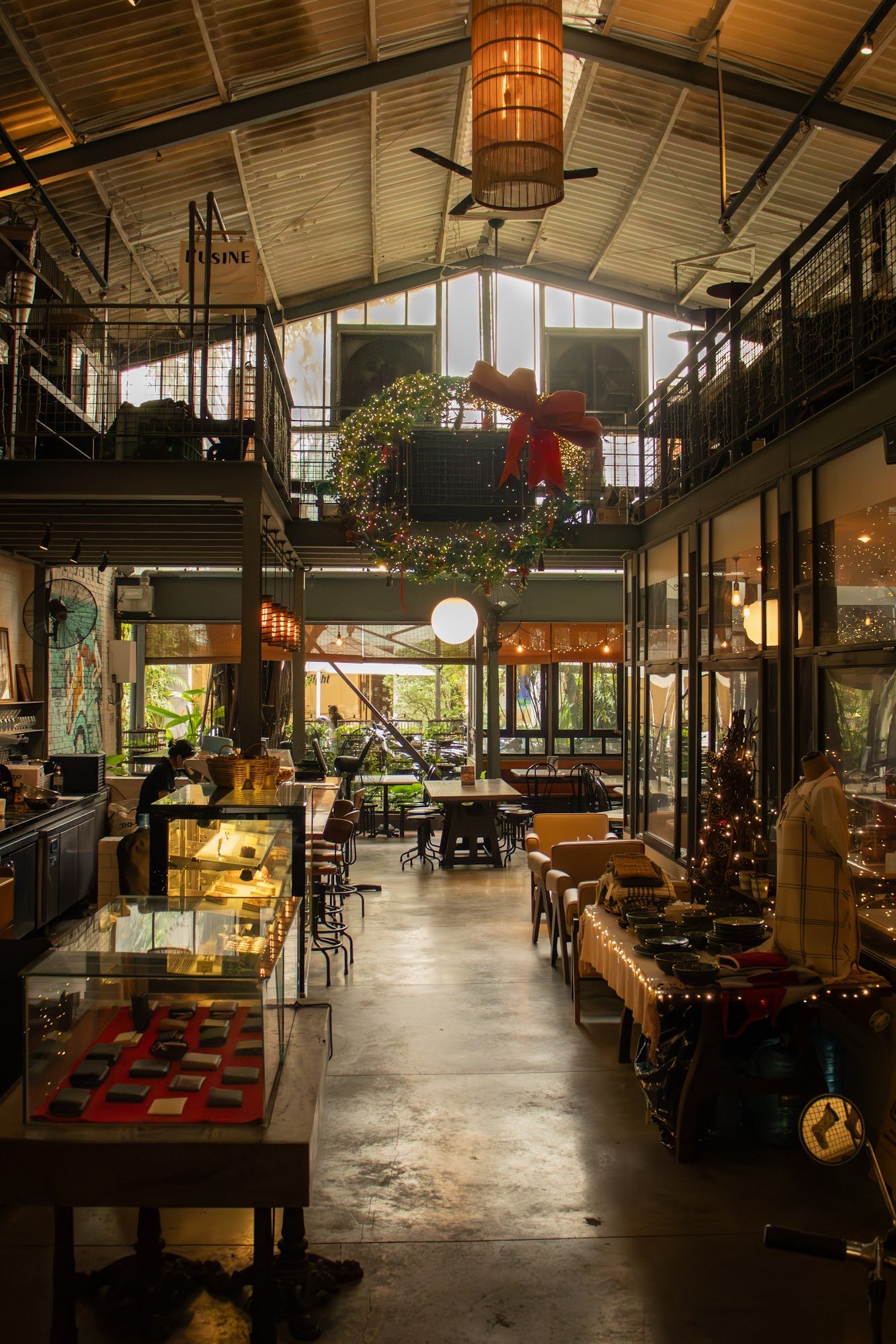 The image depicts the interior of a multi-level venue in Thao Dien, Saigon. It features an industrial-style space with high ceilings, exposed beams, a