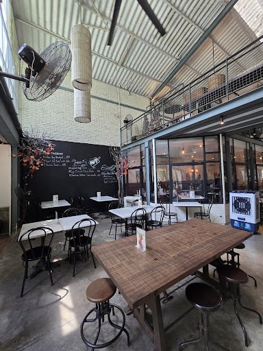 The image shows an interior view of a casual dining establishment in Thao Dien, Saigon. The space features exposed brick walls and metal beams on the 