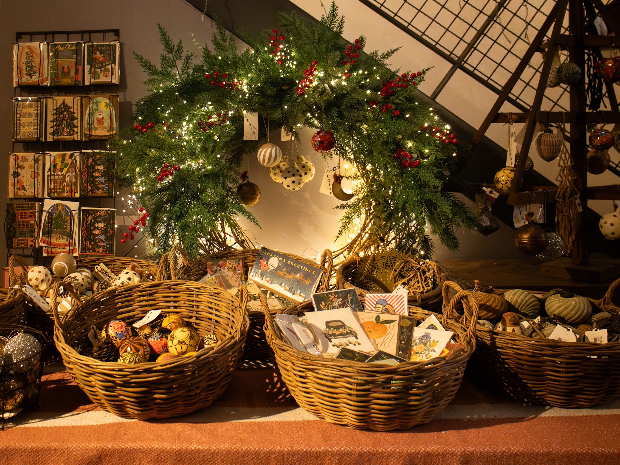 The image depicts a cozy, festive interior space, likely a shop or venue in Thao Dien, Saigon, decorated for Christmas. A large green wreath adorned w