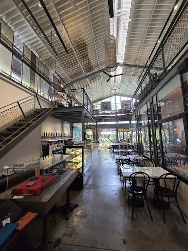 The image depicts the interior of a modern restaurant or café in Thao Dien, Saigon. It features an open layout with a high ceiling, exposed metal beam