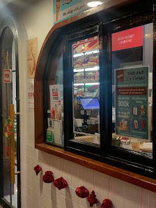 The image depicts the interior of a venue in Thao Dien, Saigon, featuring a large arched window with a wooden frame. Inside the window, promotional po