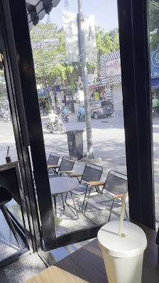 The image shows an outdoor view from a cafe or restaurant in Thao Dien, Saigon. The perspective is through large windows that offer a clear look at th