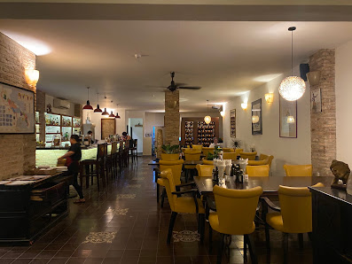 Interior of a restaurant in Thao Dien, Saigon featuring yellow chairs, tables set with tableware, brick walls, hanging pendant lights, a bar area with