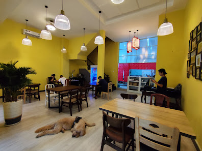 The image depicts an interior space of a cafe or restaurant in Thao Dien, Saigon with yellow walls and modern decor. The room is furnished with wooden