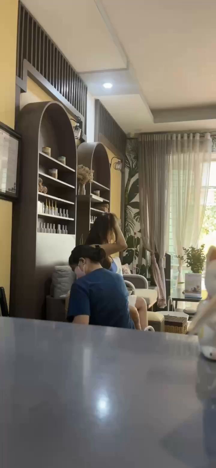 The image shows an interior space that appears to be a modern living room or lounge area with contemporary furniture and decor. There are two individu