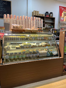 A café interior in Thao Dien, Saigon, featuring a glass display case with various beverages (iced drinks in cups) and pastries. Above the case, there