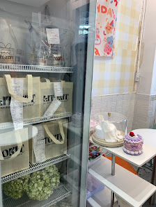 The image shows a section of an interior space that appears to be part of a cafe or bakery. There is a refrigerator with various items, including bags