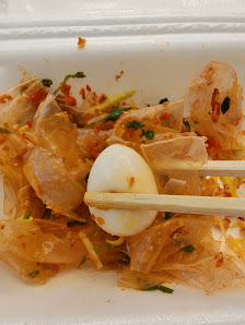 A close-up of a dish consisting of thin noodles or vermicelli topped with sliced boiled egg and garnished with herbs, possibly served in an Asian cuis